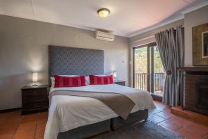 a bedroom with a large bed with red pillows at Greenway Woods Accommodation in White River +28 photos