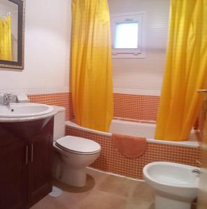 a bathroom with a yellow shower curtain and a toilet and sink at ESTUDIo SIERRALACANT in Sierra Nevada