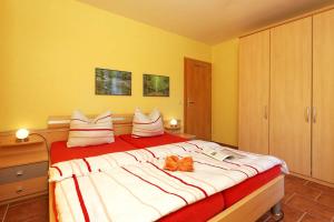 a bedroom with a large bed with white and orange pillows at Haus Grete Wohnung 12 in Ostseebad Koserow