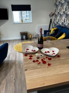 阿爾弗斯頓的住宿－Ulverston stunning 1 bedroom apartment，一张桌子上放着一瓶葡萄酒和红玫瑰
