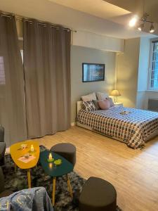 1 dormitorio con 1 cama y 2 mesas y sillas en Appartement de caractère hyper centre, en Ploërmel