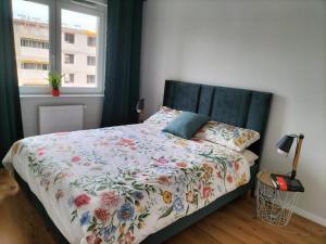 a bedroom with a bed with a floral comforter and a window at Apartment Olympia in Wrocław