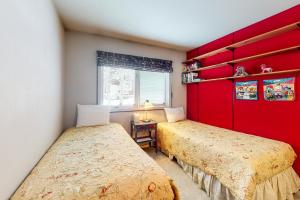 1 dormitorio con 2 camas y pared roja en Stone Creek Lodge, en Avon