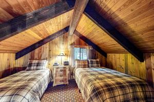 two beds in a room with wooden walls at Blue Pine Lodge in Joseph