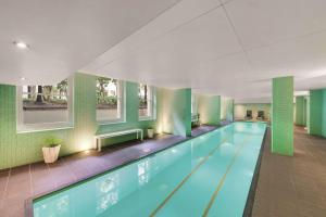 - une grande piscine dans un bâtiment aux murs verts dans l'établissement Adina Apartment Hotel Adelaide Treasury, à Adélaïde