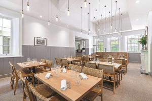 a restaurant with wooden tables and chairs and windows at Adina Apartment Hotel Adelaide Treasury in Adelaide