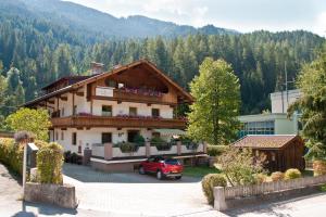 una casa con un coche rojo estacionado frente a ella en Appartements Wasserfälle, en Mayrhofen