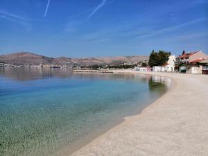 a beach with water and houses and mountains in the background at Studio apartman I&R in Ciovo