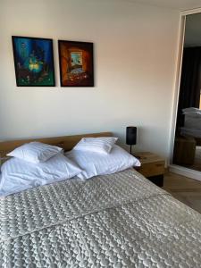 um quarto com uma cama branca com três pinturas na parede em Ogrody Pieniawskie Apartamenty 37 em Polanica-Zdrój