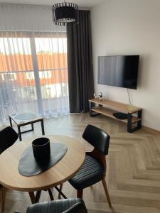 uma sala de estar com uma mesa e cadeiras e uma televisão de ecrã plano em Ogrody Pieniawskie Apartamenty 37 em Polanica-Zdrój