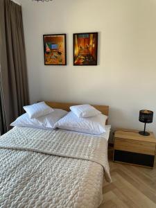 um quarto com uma cama branca com três fotografias na parede em Ogrody Pieniawskie Apartamenty 37 em Polanica-Zdrój