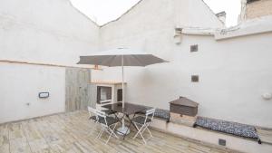 un patio con mesa, sillas y sombrilla en Apartamentos Virgen Blanca, en Toledo