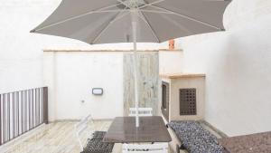 a table with an umbrella in front of a building at Apartamentos Virgen Blanca in Toledo