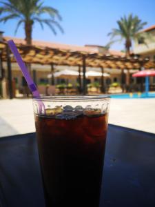 a drink sitting on a table next to a pool at Bab Al Shams Resort in Jericho