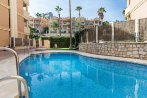 a swimming pool in a apartment complex with palm trees at BLONZU SAFARi in Benalmádena