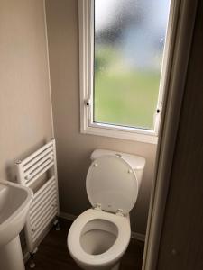 a small bathroom with a toilet and a window at Modern 3 bedroom caravan near the beach in Walton-on-the-Naze
