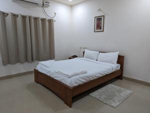 um quarto com uma cama com cobertores brancos e almofadas em White Fern Stays Serviced Apartments - Gachibowli em Hyderabad