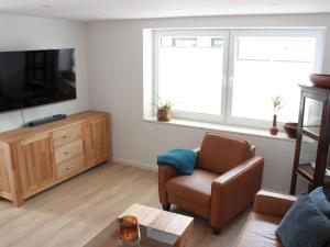 a living room with a couch and a chair and a tv at Ferienhaus Gerda in Wangerland