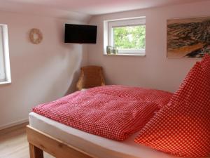 a red bed with red sheets and a window at Ferienhaus Gerda in Wangerland