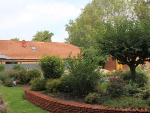 a garden with a brick wall and a tree at Ferienhaus Gerda in Wangerland