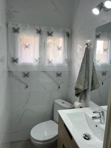 a bathroom with a toilet and a sink and butterflies on the wall at Habitación Amaya 2 in Las Corts