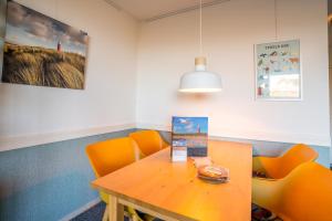 ein Esszimmer mit orangefarbenen Stühlen und einem Holztisch in der Unterkunft Appartementencomplex Juliana 68 in De Koog