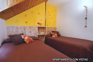 una camera con due letti e una parete gialla di Apartamentos Taüll a Tahull