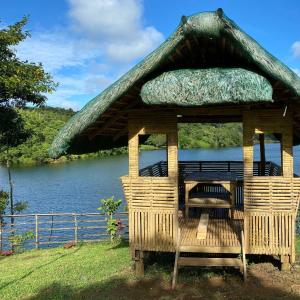 - un kiosque avec une table et des chaises à côté d'une rivière dans l'établissement Lake Of The Woods PH Entire Island Exclusive Glamping, à Cavinti