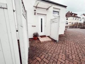 ein weißes Gebäude mit einer Tür und einer Topfpflanze in der Unterkunft Linden Apartment Wolfenbüttel in Wolfenbüttel