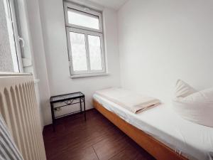 a small white room with a bed and a window at Linden Apartment Wolfenbüttel in Wolfenbüttel