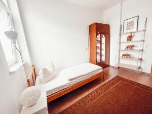 a white room with a bed and a shelf at Linden Apartment Wolfenbüttel mit Ladestation für E-Auto in Wolfenbüttel +3 photos
