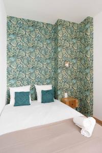 una camera da letto con un grande letto con carta da parati verde di Les Petits Pavillons Standing Clim Vieux-Port - MaisonMars a Marsiglia
