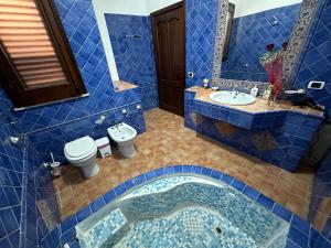 a blue tiled bathroom with a sink and a toilet at Villa Dalila in Lampedusa