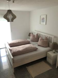 een wit bed met kussens in een kamer bij Ferienwohnung Villa Hygge in Mitterteich