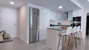 cocina con armarios blancos y barra con taburetes en Dunas Beach II Apartment, en Torrox Costa