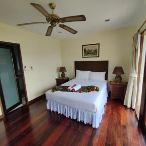 Schlafzimmer mit einem großen Bett und einem Deckenventilator in der Unterkunft Baiyok Villa seaview and edge pool in Patong Beach