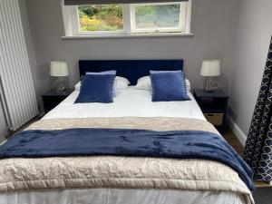 a bedroom with a large bed with blue pillows at Bracken Lodge in Brighouse