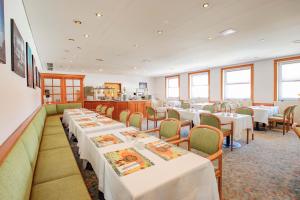 une salle à manger avec des tables et des chaises blanches dans l'établissement Hotel Astor, à Altenburg