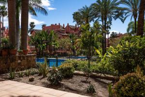 um resort com piscina e palmeiras em Precioso apartamento de planta baja en Las Salinas, Estepona em Estepona