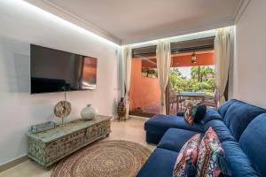 uma sala de estar com um sofá azul e uma televisão em Precioso apartamento de planta baja en Las Salinas, Estepona em Estepona