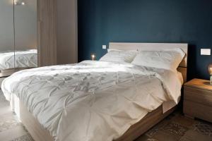 um quarto com uma grande cama branca e uma parede azul em Casa Gli Olmi - centro storico em Bracciano