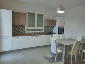 a kitchen with white cabinets and a table and chairs at La casetta del Fico d'India in Marsala