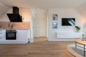 a kitchen with white cabinets and a tv on the wall at Moderne Küstenbutze in Nordseenähe (Butze #3) in Mildstedt