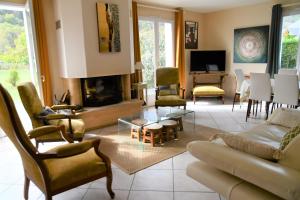 sala de estar con sofá, sillas y chimenea en Maison Marguerite en Bordères-Louron