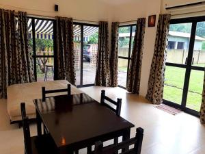 a dining room with a table and chairs and windows at Chalet Ahaz, the place of privacy with outside sitting in Karjat