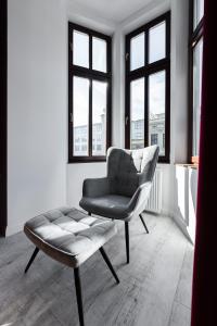 una sedia e uno sgabello in una stanza con finestre di Apartamenty Centrum nowoczesny design - Dream Apart a Bielsko-Biała