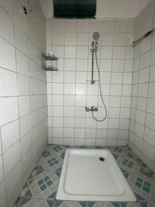 y baño de azulejos blancos con ducha y bañera. en Appartement à 2 pas de l'ilôt de Sada., en Sada