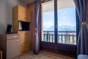 Habitación con una gran puerta de cristal con vistas. en Studio with balcony and beautiful view - Alpe d'Huez - Welkeys en LʼHuez