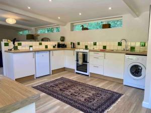 a kitchen with white cabinets and a washer and dryer at Little Innsacre in Bridport