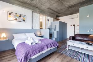 a bedroom with a large bed with purple blanket at Bridge It - Suites & Views in Vila Nova de Gaia